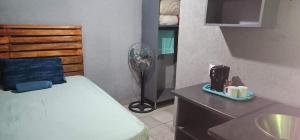 a small bedroom with a bed and a fan at Zairasbread in White River