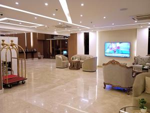 a lobby with a waiting room with chairs and a tv at Sendan Residence in Dammam