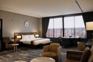 a hotel room with a bed and a table and chairs at Leaf Suites - أجنحة ليف in Ar Rass +35 photos