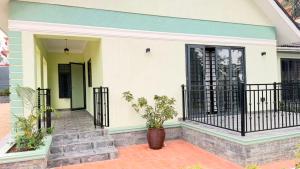 a white house with a black gate and stairs at EZER HOMEs in Kampala