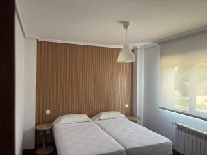 a bedroom with two white beds and a window at Apartamentos La Reserva Isla "Playa de la Cava" in Isla