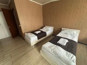 two beds in a small room with wooden floors at Green House in Karakol +9 photos