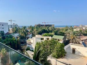 Blick auf eine Stadt mit Palmen und dem Meer in der Unterkunft Emeraude avec salle de sport in Dakar