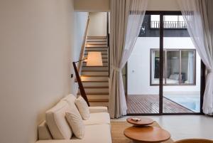 a living room with a white couch and a staircase at Qabalah Villa Private Pool & Rooftop Garden Stylish 2BR Retreat near Bang Tao in Ban Pak Lak