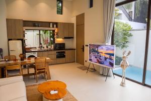 a living room with a tv and a kitchen at Qabalah Villa Private Pool & Rooftop Garden Stylish 2BR Retreat near Bang Tao in Ban Pak Lak