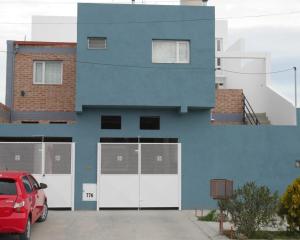 a blue building with a red car parked in a parking lot at Ayinmai departamento C in Trelew