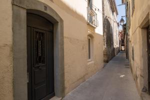 an alley with a black door on the side of a building at Duplex Terrasse Jacuzzi Privatif & Vue Cévennes in Saint-Jean-du-Gard