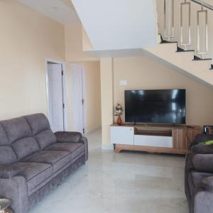a living room with a couch and a flat screen tv at Malliga Farm House in Turinjāpuram