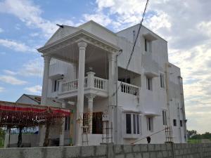 a white building with a porch on top of it at Malliga Farm House in Turinjāpuram +11 photos
