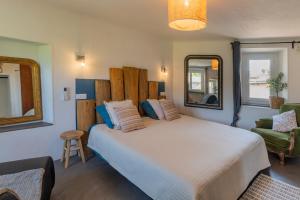 a bedroom with a large white bed and a chair at Duplex Terrasse Jacuzzi Privatif & Vue Cévennes in Saint-Jean-du-Gard