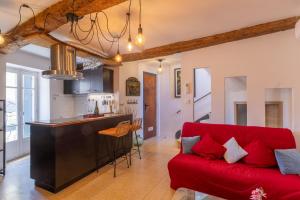 a living room with a red couch and a kitchen at Duplex Terrasse Jacuzzi Privatif & Vue Cévennes in Saint-Jean-du-Gard
