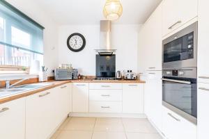 a kitchen with white cabinets and a clock on the wall at Convenient & cosy 3 bed house in Newport
