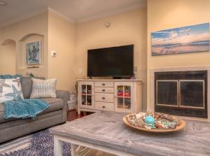 a living room with a tv and a couch and a fireplace at 2502 Chateau by the Green in Seabrook Island