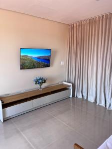 a living room with a couch and a tv on the wall at Residencial Canto dos Passarinhos - Loft e Apartamentos in Alto Paraíso de Goiás