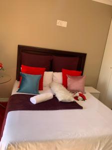 a bed with colorful pillows on top of it at Ecogreen on OR Tambo in Kempton Park