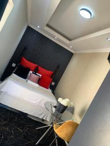 a bedroom with a bed with red pillows at Ecogreen on OR Tambo in Kempton Park