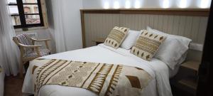 a bedroom with a bed with white sheets and pillows at O retiro da Trabe in Viveiro