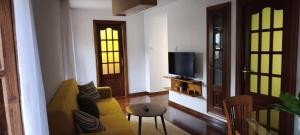 a living room with a yellow couch and a tv at O retiro da Trabe in Viveiro