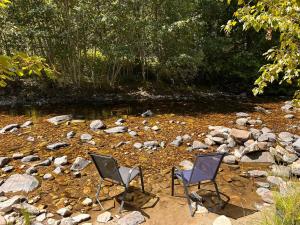 two chairs sitting on the rocks near a river at Privet creek side glamping in Chase