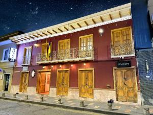 ein rotes Gebäude mit Holztüren an einer Straße in der Unterkunft Hotel Casa Ruth Cuenca in Cuenca