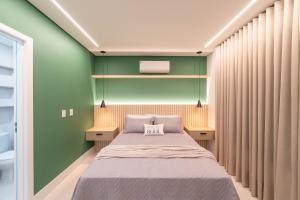 a bedroom with a bed with green walls and curtains at Apartamento em Condomínio Frente-Mar com Piscinas, Jacuzzi Aquecida, Sauna, Academia, Brinquedoteca, Churrasqueira na Sacada, Cozinha Completa in Piçarras +29 photos