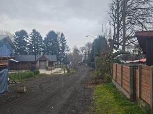 a dirt road with a fence and a house at Cabaña Lafken in Panguipulli