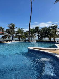 a large swimming pool with palm trees in the background at Hotel Rede Beach in Trairi