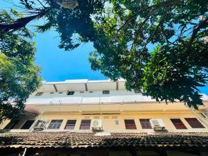 a white building with trees in front of it at Akkaraipattu Guest House in Akkaraipattu