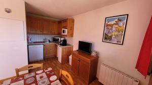 a kitchen with a table and a tv on a wall at Sunny chalettt great view ski in Puy-Saint-Vincent +27 photos