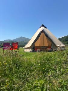 a tent in a field of grass with two chairs at Wild Camping Teepee in Capel Curig