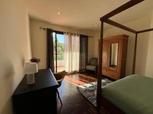 a bedroom with a bed and a desk with a lamp at Grande Maison Mandrosoa in Abohijanahary