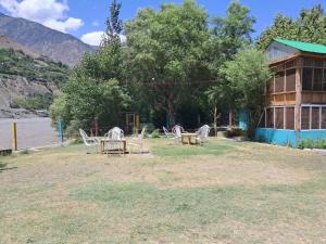 a group of chairs and tables in front of a building at Fish Lake Park Guest House in Chitral