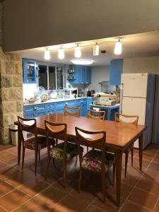 a kitchen with a wooden table and chairs and blue cabinets at Dar el Maasser in Maasser El Chouf