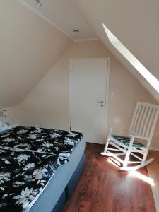 a bedroom with a bed and a white chair at Auszeit an der Jümme in Detern