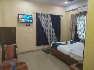 a bedroom with a bed and a tv on the wall at Woohoo Hotels in Patna