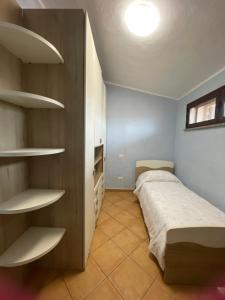 a small bedroom with a bed and shelves at Nenniri's house in Villamassargia