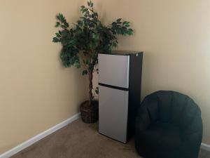 a refrigerator in a room with a chair and a plant at Guest Suites in Conley