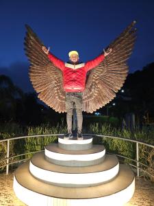 a man standing on top of a statue with wings at otro rollo en Jilotepec in Jilotepec