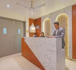 a man standing at a counter in a lobby at Hotel Church House - Rohini I Near Metro I Spacious Rooms I Friendly Staff I Most Preferred Hotel In Rohini in Delhi