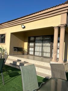 a patio with chairs and a table in front of a house at Piink Lopez in Manzini