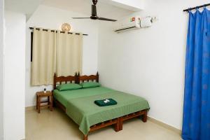 a bedroom with a bed with green sheets and a ceiling fan at GOOD KARMA INN Apartment in Cochin