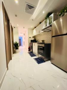 a kitchen with white tile floors and a stainless steel refrigerator at Vogue Inn in Abu Dhabi