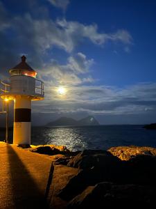 a lighthouse sitting on the shore of the ocean at Astra Whale - Waterfront Boutique Hostel in Lofoten in Kabelvåg