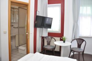 um quarto com uma cama, uma mesa e uma televisão em Hotel An der Kapelle em Meiningen