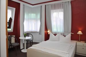 a bedroom with a white bed with red walls and windows at Hotel An der Kapelle in Meiningen