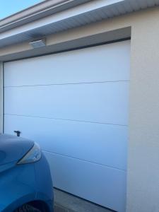 a white garage door on the side of a building at Amélia HOST chambre climatisée in Saint-Rémy-lès-Chevreuse