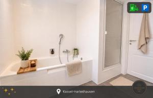a white bathroom with a tub and a shower at Ferienwohnung Kassel mit Ladesäule in Kassel