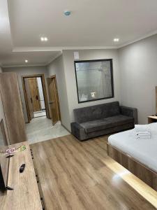 a bedroom with a bed and a couch and a table at Palace&Spa Rooms in Shymkent