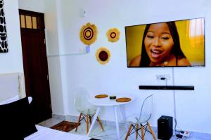 a tv hanging on a wall with a table and chairs at Soft stay homes in Mombasa
