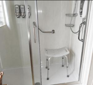 a bathroom with a shower and a stool in it at lake District cottage in Bootle +21 photos